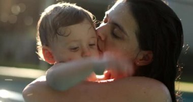Mother embracing and kissing baby at the swimming pool
