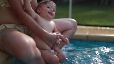 Anne bir yaşında bebeğe havuz suyuna alışmayı öğretiyor.