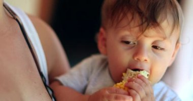Happy baby eating corn. One year old toddler eats healthy natural snack