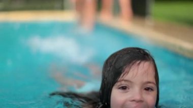 Child girl swimming at pool during summer day. Cute adorable small girl playing and splashing water
