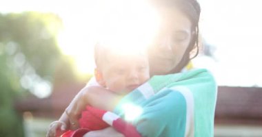 Mother caring and loving baby child. Mom kissing infant wrapped in towel after pool