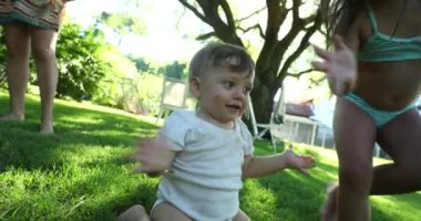 Baby clapping hands outside with older sister. Happy kids feeling joy during summer day