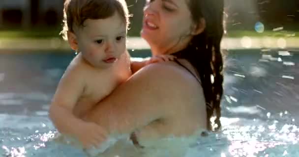 赤ん坊の子供はプールで水を撒く幼児の息子の世話をするお母さん — ストック動画