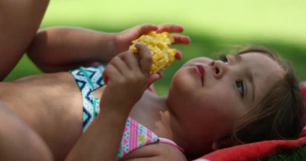 在大自然之外的草地上吃玉米时 可爱可爱的小女孩不停地做着白日梦 — 图库视频影像