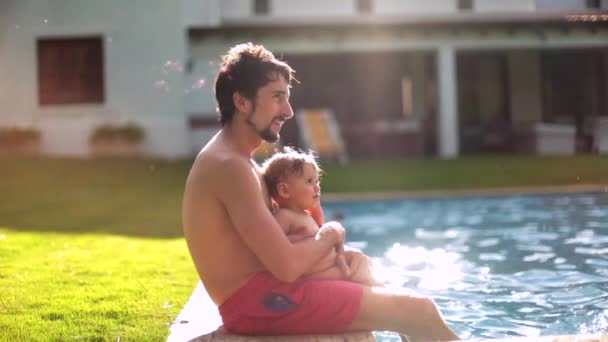 父と赤ちゃんの間のカジュアルな家族の瞬間幼児一緒にでスイミングプール屋外 — ストック動画
