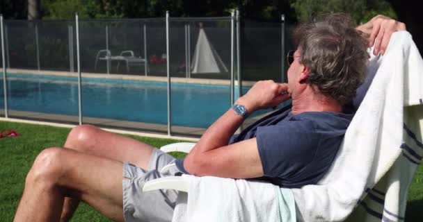 Homem Mais Velho Aposentado Descansando Fora Com Vista Para Piscina — Vídeo de Stock