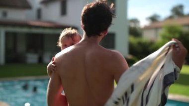 Babamızın kucağında küçük bir çocuk, açık havuzda yüzüyor. Babasının küçük oğluyla bağ kurması.