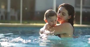 Mother kissing baby son at the pool