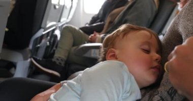 Cute baby asleep during flight. Infant toddler sleeping inside airplane