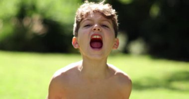 Yavaş çekimde avazı çıktığı kadar bağıran çocuk. Kızgın çocuk kameraya bağırıyor.