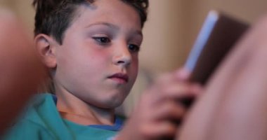 Tablet ekranının önündeki çocuklar online oyun oynuyorlar. Çocuk tutma teknolojisi aygıtı