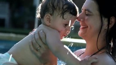 Anne ve bebek havuz suyunda birlikte. Gerçek hayatta otantik bebek ve ebeveyn yakınlaşması ve kucaklaşması