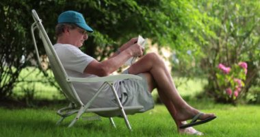 Older retired man reading book outdoors. Senior man reading novel story