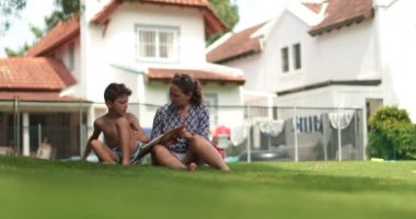 Dürüst bir anne dışarıda oğluyla ödev yapıyor.