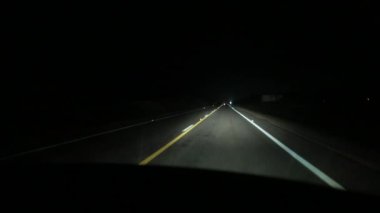 Driving on highway road at night. Driver POV in pitch dark with headlights
