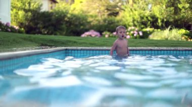 Havuzda hoplayıp zıplayan mutlu çocuk.