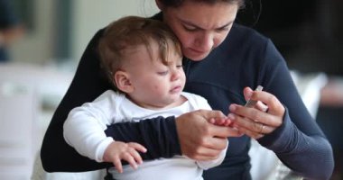 Mother trimming baby nails. Toddler infant on mom lap cutting clipping son nail