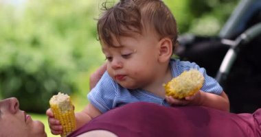 Dışarıda mısır koçanı yiyen şirin bir bebek. Sevimli bebek dışarıda sağlıklı bir şeyler atıştırıyor.