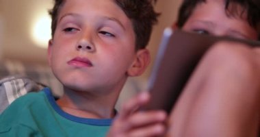 Evdeki gizli çocuk elinde tablet cihazıyla ekrana bakıyor. Teknoloji kullanan gizli çocuklar.