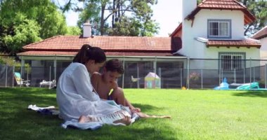 Anne, oğluna arka bahçede okumayı öğretiyor.