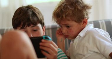 Kardeşler ellerinde tablet aygıtıyla içeriği izliyorlar