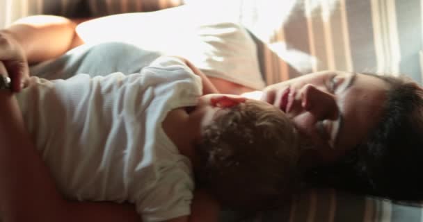 Tired mother asleep on sofa with baby infant. Real life authentic mom napping with child 606304072