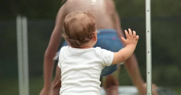 幼児は夏の日の間にプールの水の中で遊んで子供を見てプールフェンスにもたれて — ストック動画