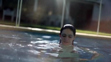 Yüzme havuzunda yaz tatilinin keyfini çıkaran mutlu bir kadın sudan yavaş çekim 120 fps hızla çıkıyor.