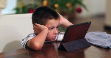 Evde tablet cihazıyla hipnotize edilen çocuk. Çocuk çizgi film izliyor.