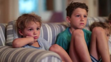 Çocuklar geceleri kanepede televizyon izliyor.