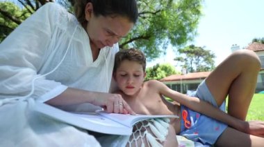 Anne çocuğuna dışarıda okumayı öğretiyor.