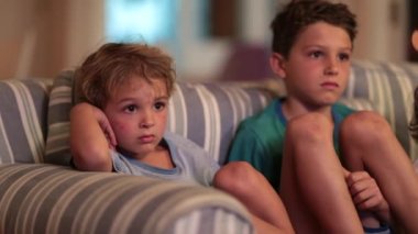 İki kardeş birlikte kanepede TV 'de içeriği izliyorlar.