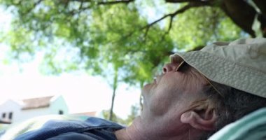 Senior man napping outside under a tree. Older retired man sleeping and resting