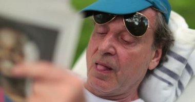 Dışarıda gazete okuyan sıradan yaşlı bir adam.