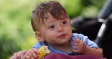 Mısır yiyen tatlı bir bebek. Düşünceli çocuk abur cubur yerken düşünüyor