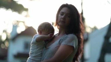 Gerçek hayatta anne gün batımında bebeğini kucağında tutuyor.