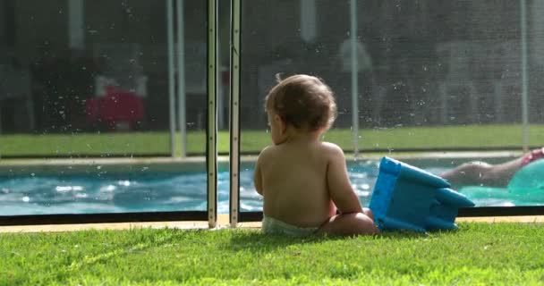 Малыш Тоддлер Наблюдает Семейными Играми Бассейне Младенца Сидящего Траве Дворе — стоковое видео