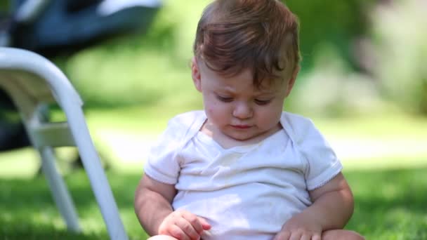 美しい赤ちゃんの幼児は 裏庭を発見する草の上に座って — ストック動画