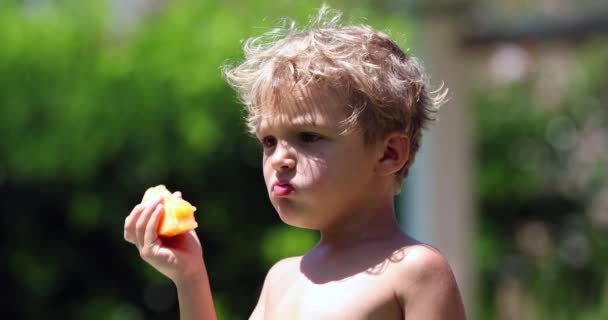 Niño Olfateando Afuera Mientras Mastica Fruta — Vídeos de Stock