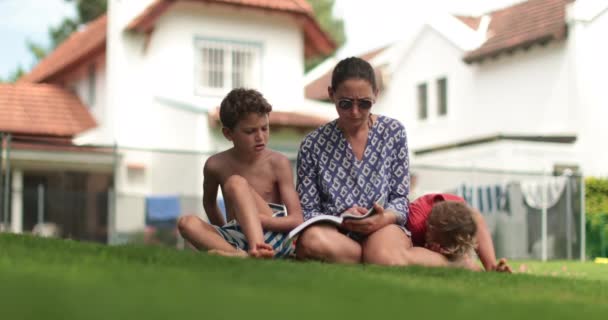 裏庭で子供の息子を指導する母親 ママ教師子供を読むために — ストック動画