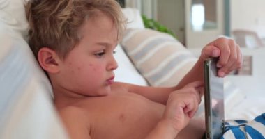 Boy lying on sofa using smartphone