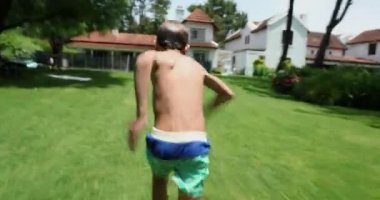 Aktif bir çocuk çimde koşuyor ve havuz suyuna atlıyor