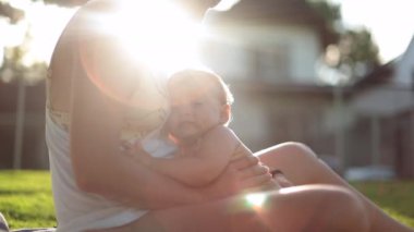 Baby and mother together outside in sunlight with lens-flare