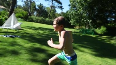 Çocuk bahçeye koşuyor ve yavaş çekim 120 fp hızla havuza atlıyor.