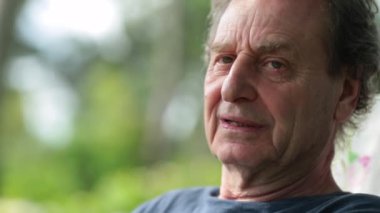 Senior man in 70s portrait smiling to camera outdoors