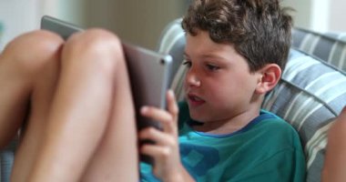 Oyun tarafından hipnotize edilen çocuk, tablet aygıtı kullanarak oynayan çocuk