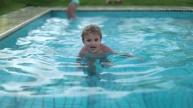 Mutlu çocuk havuz suyunun içinde tatilin tadını çıkarıyor.