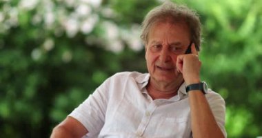 Retired older man talking on cellphone. Senior person speaking on phone, candid and authentic