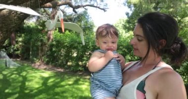 Mom kisses baby toddler outdoors, casual real life moment between mother and child