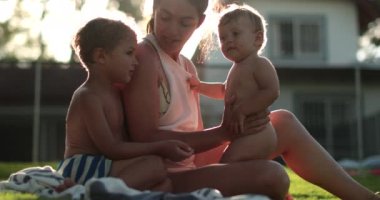 Anne ve çocuklar gün batımında bahçenin dışında.